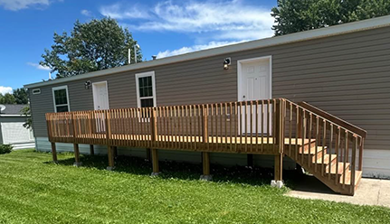 Brown manufactured home with outdoor deck and staircase