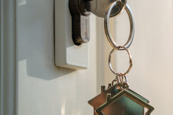 Key hanging out of door lock with a dangling house shaped key chain