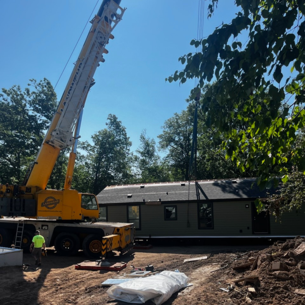 Factory built modular home being set on the foundation with a crane.