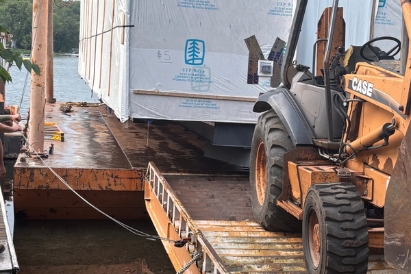 Home being loaded onto a barge by machinery.